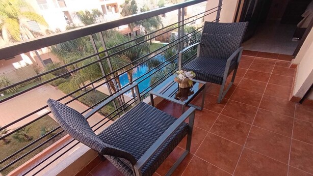 A balcony with two wicker chairs, a small table, and a decorative item. - Beautiful Apartment in Marrakech, GUELIZ (Marrakech)