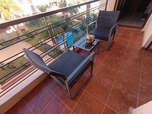 A balcony with two wicker chairs, a small table, and a decorative item. - Beautiful Apartment in Marrakech, GUELIZ (Marrakech)