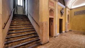 Una scala conduce a una porta, una statua e un pavimento con motivo a spina di pesce.