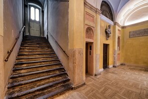 Eine Treppe führt zu einer Tür, einer Statue und einem Fußboden mit Fischgrätmuster.