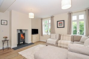 Una sala de estar con chimenea, sofá, televisor y ventanas.