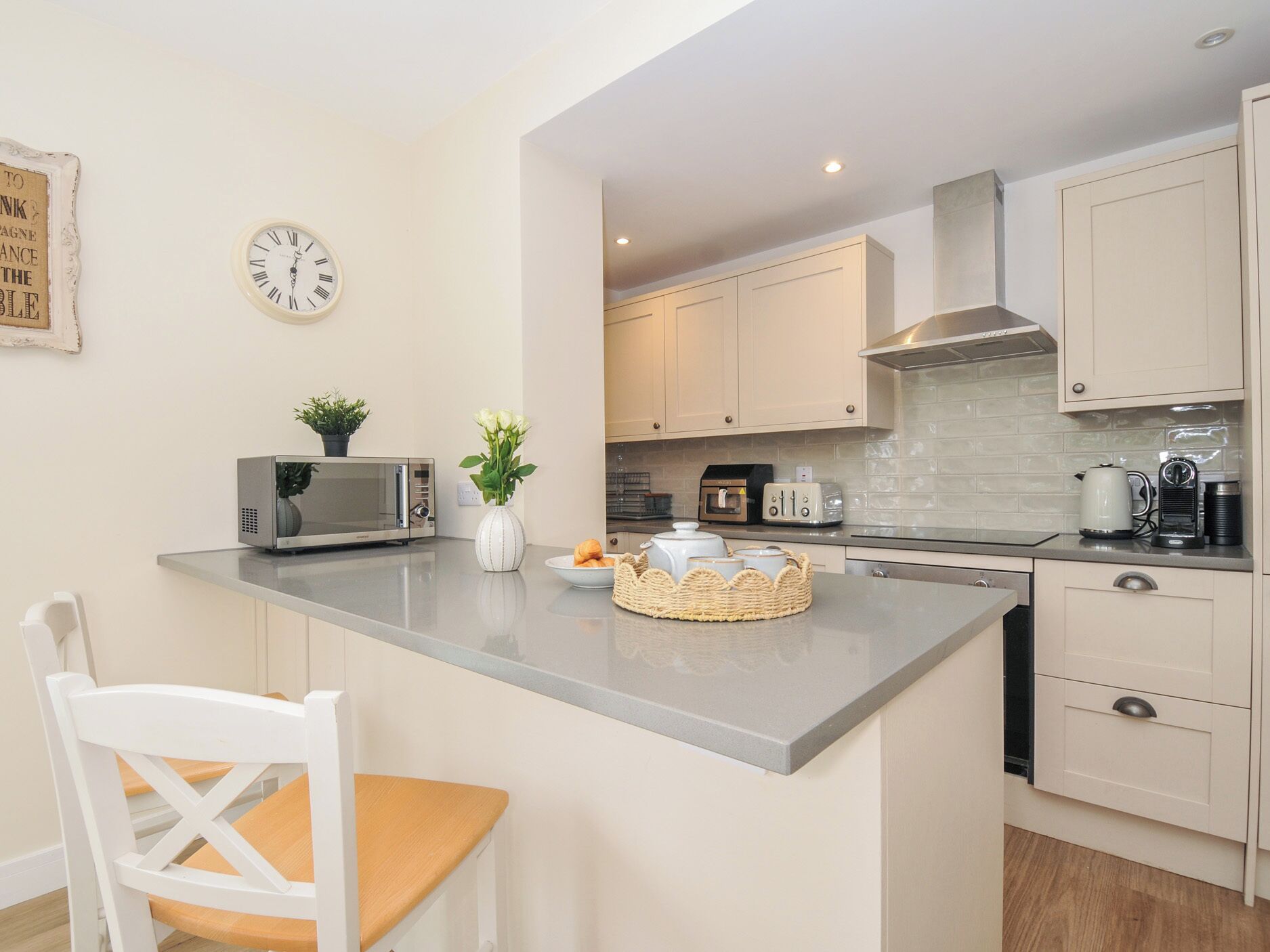 A modern kitchen with a central island, white cabinetry, a microwave, a toaster, and a kettle.