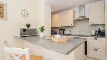A modern kitchen with a central island, white cabinetry, a microwave, a toaster, and a kettle.