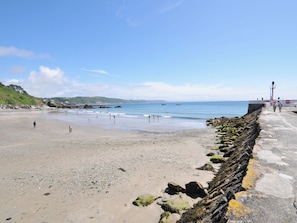 A beach with a rocky breakwater, calm sea, and distant hills. - Barton House (Looe)