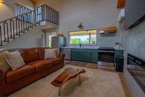 A modern kitchen with a dining area, a staircase, and a living room with a leather sofa. - Stay on the Wine Trail - Luxury 5-Acre Fredericksburg Private Retreat (Fredericksburg)