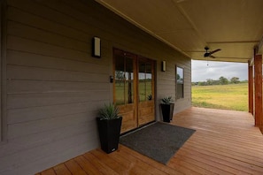 A covered porch with wooden flooring, a ceiling fan, and a view of a grassy field. - Stay on the Wine Trail - Luxury 5-Acre Fredericksburg Private Retreat (Fredericksburg)