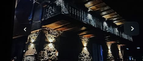 Un teléfono inteligente muestra una página web con una imagen oscura del exterior de un edificio, posiblemente un hotel, con una escalera y detalles de piedra.