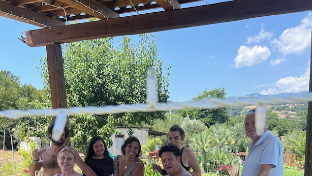 Un groupe de personnes se trouve autour d’un jacuzzi, protégé par une pergola.