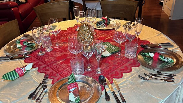 A dining table set for a meal with multiple chairs, a centerpiece, and various tableware.
