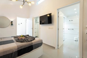 Une chambre à coucher moderne avec un lit, un téléviseur à écran plat, un miroir et un dressing.