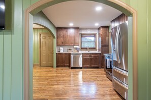 A kitchen with wooden cabinets, a stainless steel refrigerator, and a dishwasher.