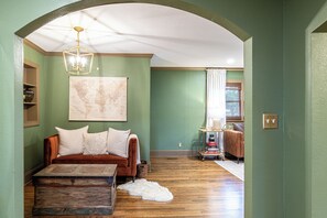 Una habitación con sofá, un mapa en la pared, suelo de madera y una lámpara en el techo.