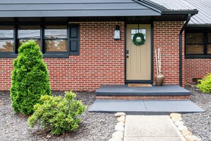 Un bâtiment en briques avec une porte d’entrée, un petit porche et une guirlande accrochée à la porte.