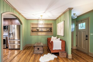 A kitchen with stainless steel appliances, a wooden floor, a red sofa, and a white rug.