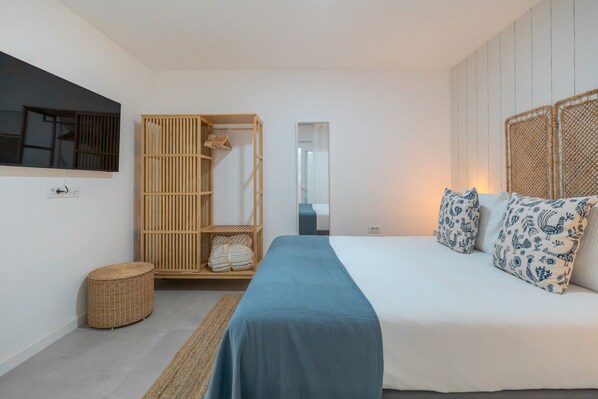 Un dormitorio con cama, armario, espejo y una pequeña cesta redonda de mimbre.