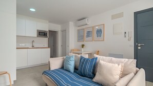 Un salon moderne avec un canapé, une petite table et une cuisine en arrière-plan.