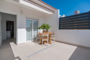 A modern patio with a table and chairs, a potted plant, and a sliding glass door leading to an interior space. - Vacation Apartment 'Isabel 3' with Balcony, Wi-Fi and Air Conditioning (Guargacho)