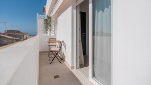 Een balkon met een tafel en stoelen, een schuifpui en uitzicht op de stad.