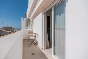Ein Balkon mit Tisch und Stühlen, eine Schiebetür und Blick auf die Stadtlandschaft.