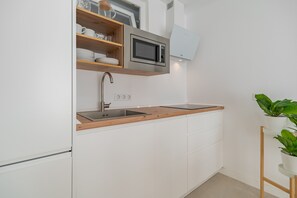 Eine moderne Küche mit weißen Schränken, einer Edelstahl-Spüle, einer Mikrowelle und einer Holz Arbeitsplatte.