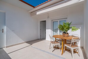 Un patio con una mesa de madera redonda, cuatro sillas y una planta en maceta.