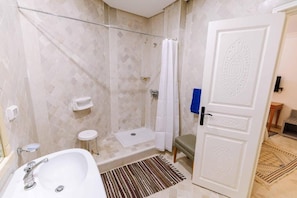A bathroom with a shower, a sink, a toilet, and a door with a decorative panel. - Dar Dhiafa Paul Klee Kairouan (Kairouan)