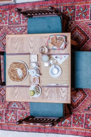 A wooden table with a breakfast setting including a plate of pancakes, a bowl of fruit, and various condiments. - Dar Dhiafa Paul Klee Kairouan (Kairouan)