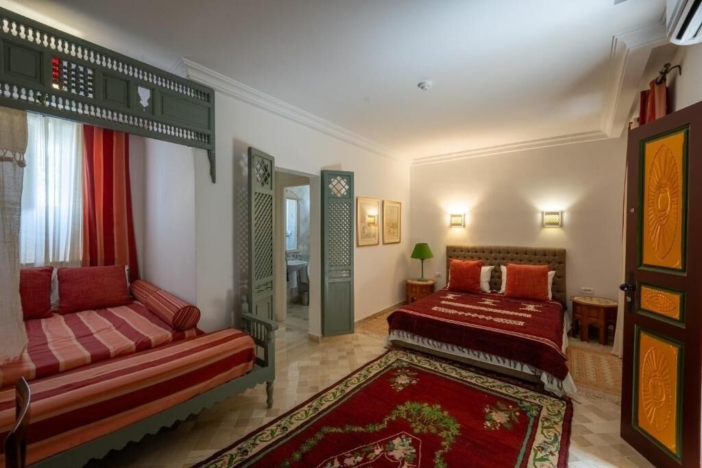 Una habitación con cama, sofá, lámpara y puerta con paneles decorativos.