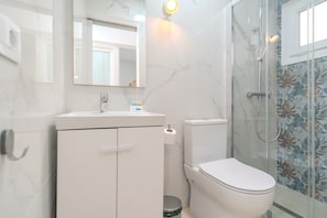 Een badkamer met toilet, wastafel en douche.