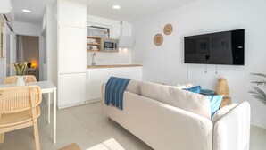 Un espacio habitable moderno con sofá, televisión y área de cocina.