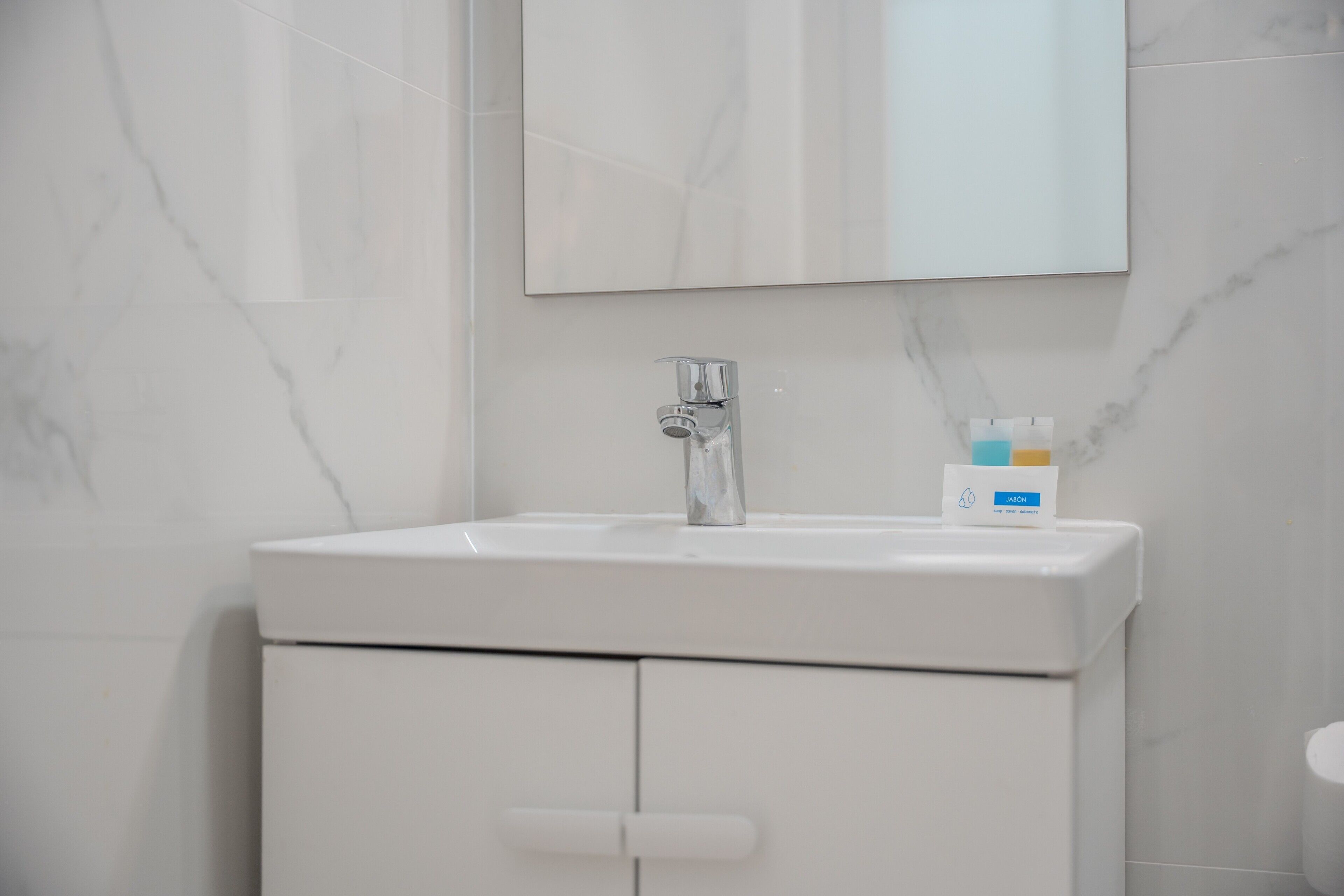 Un bany amb un rentamans blanc, un mirall i un armari.