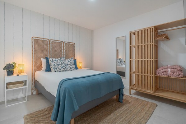 Een slaapkamer met een bed, nachtkastje, lamp en kledingkast.