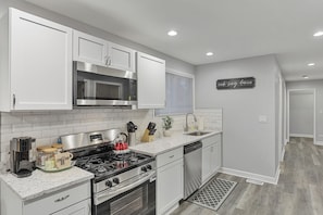 Una cocina moderna con muebles blancos, electrodomésticos de acero inoxidable y salpicadero.