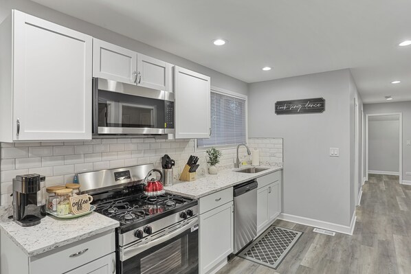 A modern kitchen with white cabinetry, stainless steel appliances, and a backsplash.
