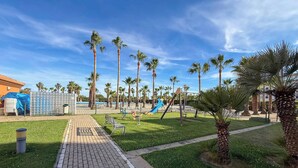 A park with palm trees, a playground, and a pathway. - Spacious Penthouse • Large Sun Terraces • HYA01 (Isla Canela)