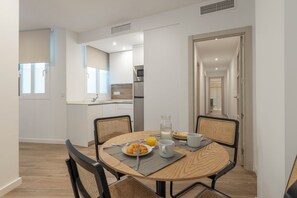 A modern dining area with a round table, chairs, and breakfast items. - BIBO SUITES CASA NAWAL (Granada)