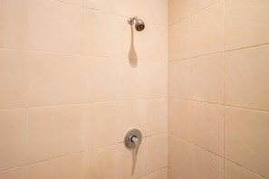 Eine Dusche mit Handbrause und Armaturen an der Wand.