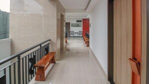 A corridor with a wooden bench, a red door, and a view into a room with a dining area. - Sweet Karina Hotel Pasteur (Bandung)