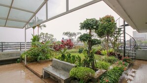 A covered outdoor garden area with a bench, various plants, and a staircase. - Sweet Karina Hotel Pasteur (Bandung)