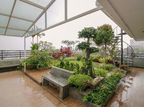 Ein überdachter Gartenbereich mit einer Bank, verschiedenen Pflanzen und einer Treppe.