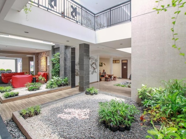 Un espace intérieur vaste et lumineux, comprenant un coin salon, des plantes et un pilier en pierre.