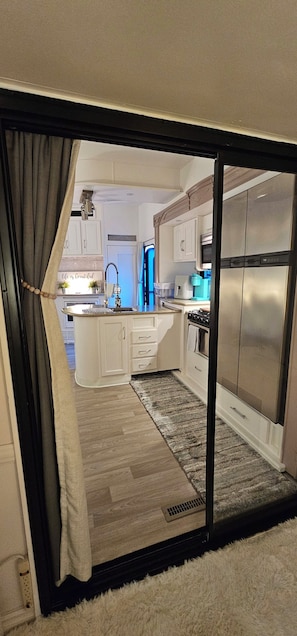 Una cocina moderna con gabinetes blancos, un refrigerador de acero inoxidable y un horno empotrado.
