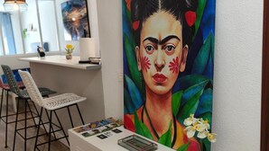 Ein modernes Interieur mit einer weißen Konsole, einem farbenfrohen Gemälde und einer Sitzecke mit Stühlen und einem Tisch.