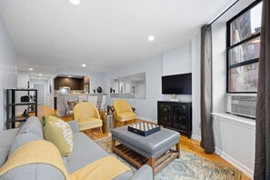 A modern living room with a sofa, armchairs, a coffee table, and a TV. - The Lenox - 3rd Floor (New York)