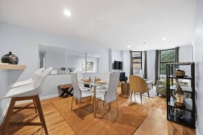 A modern dining area with a glass table, white chairs, and a wooden floor. - The Lenox - 3rd Floor (New York)