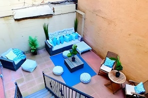 Una terraza en la azotea con asientos, una mesita y barandilla.