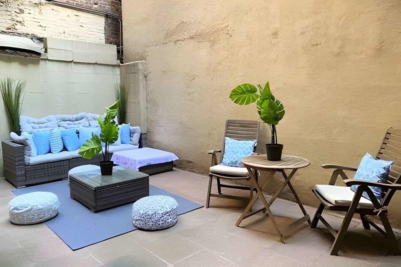 A cozy outdoor seating area with a sofa, chairs, a small table, and potted plants.