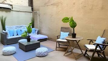 A cozy outdoor seating area with a sofa, chairs, a small table, and potted plants.
