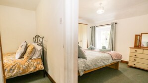 A bedroom with a bed, a dresser, and a window with curtains.
