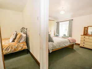 A bedroom with a bed, a dresser, and a window with curtains.